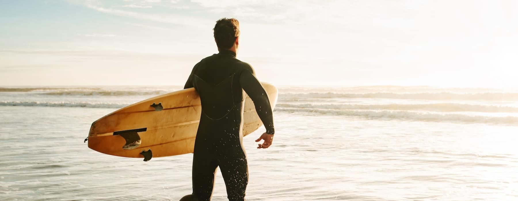 a man with a surf board on a bright beach